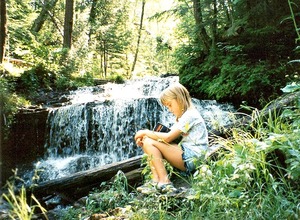 Child reading by waterfall. Image by Julie Falk. Child reading by waterfall. Image by Julie Falk.